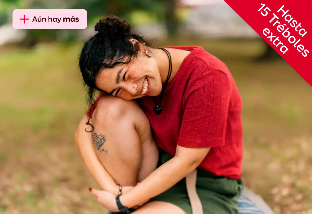 mujer sentada en el campo abraza su rodilla y sonrie