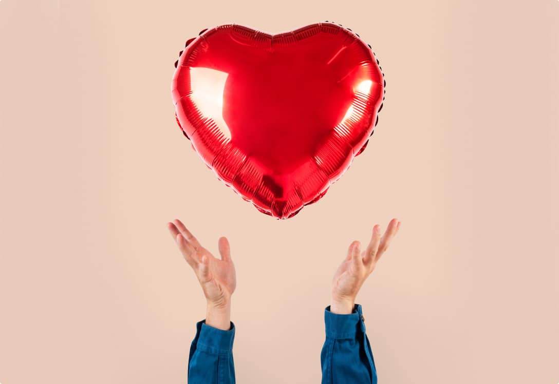 manos lanzando un globo en forma de corazón