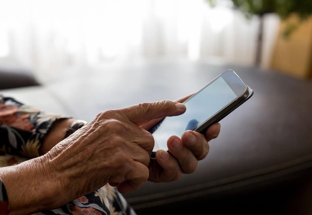 mano de una mujer mayor consultando un movil