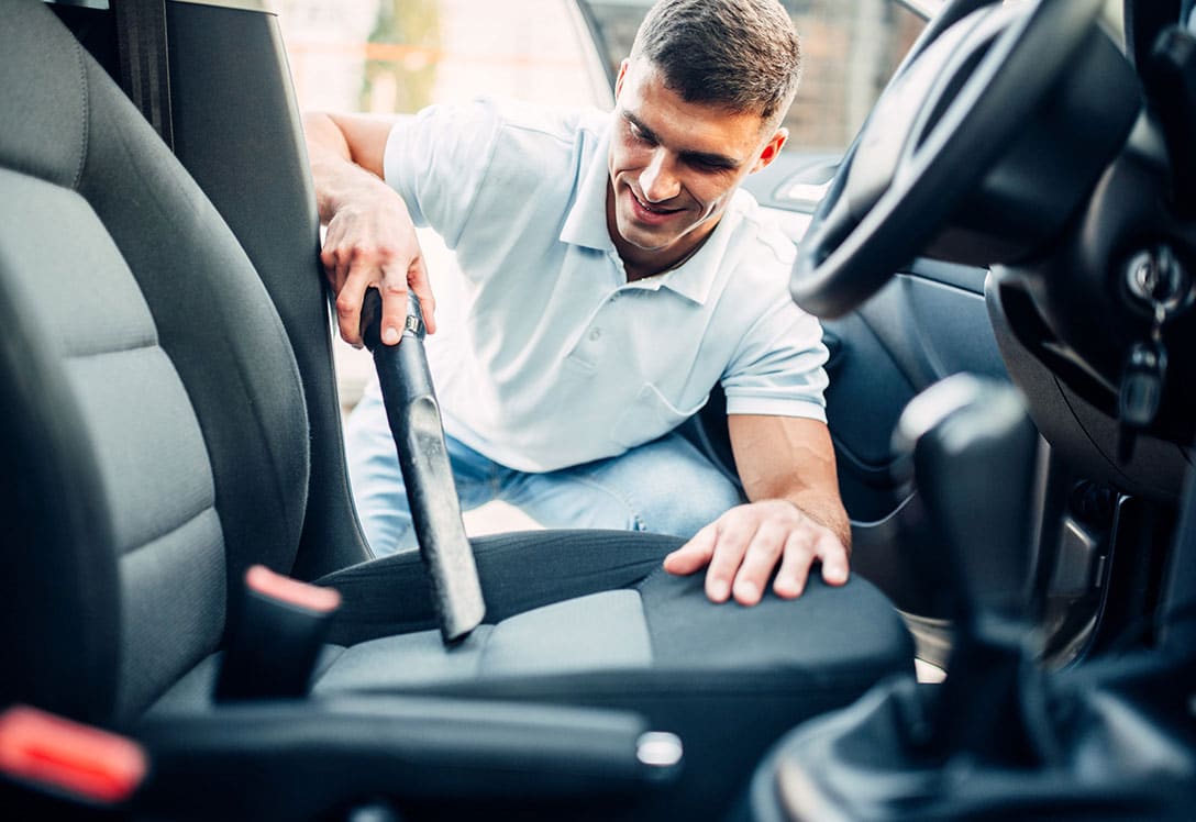 como-limpiar-el-coche-1 Hombre usando productos para limpiar la tapicería del coche