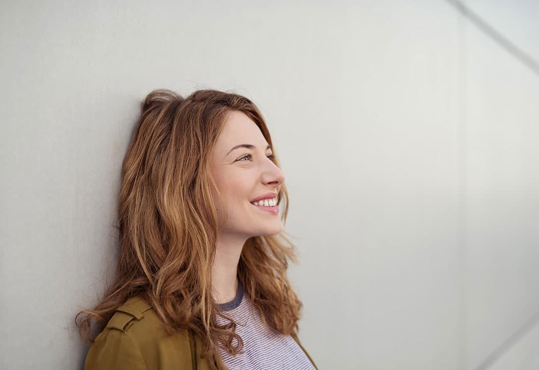 mujer apoyada en pared sonriendo