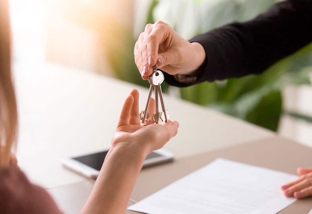 manos recibiendo llaves de vivienda frente un contrato