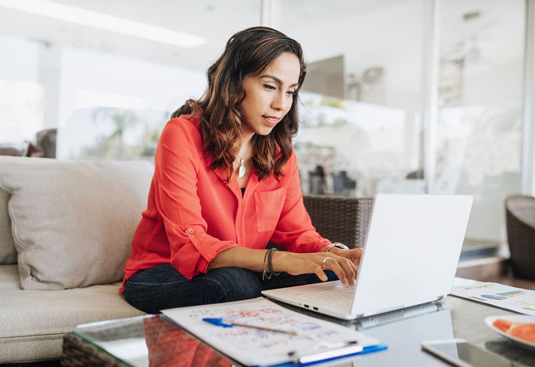 mujer consultando portátil desde el sofá