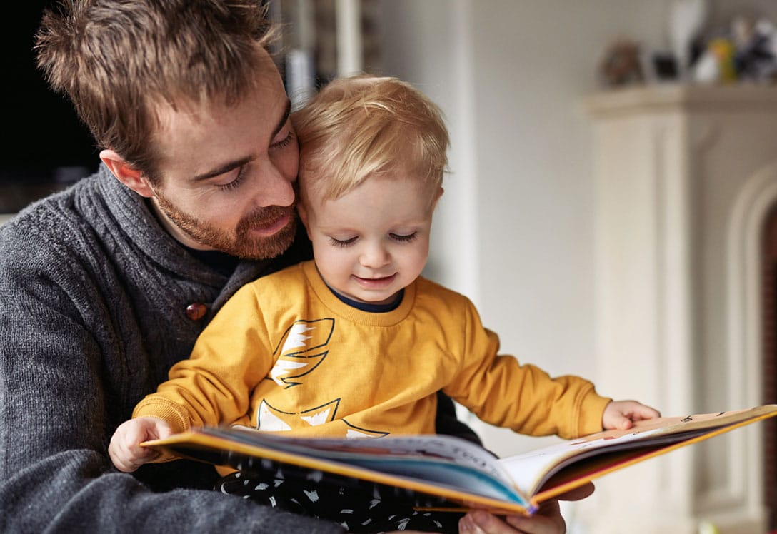 padre con hijo pequeño mirando un libro