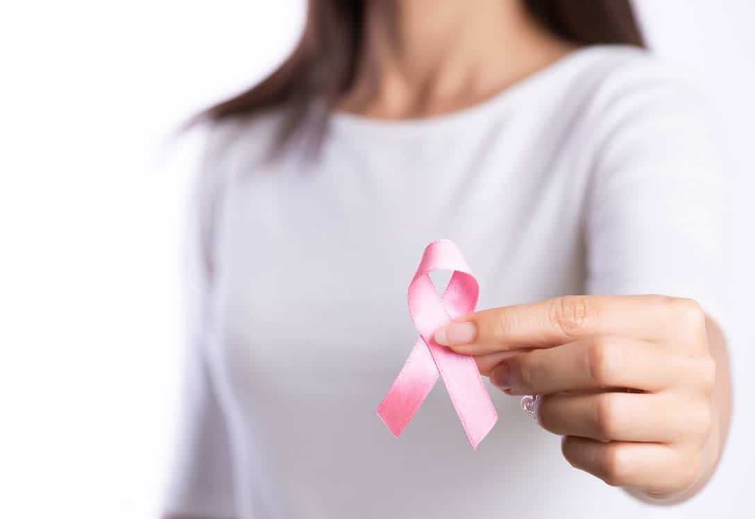 mujer mostrando lazo rosa contra el cáncer de mama