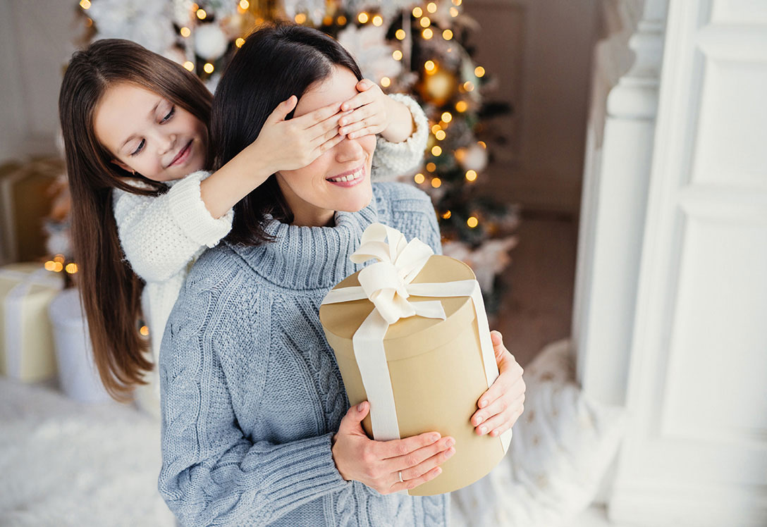 Niña tapando a los ojos a su madre antes de que habra un regalo personalizado