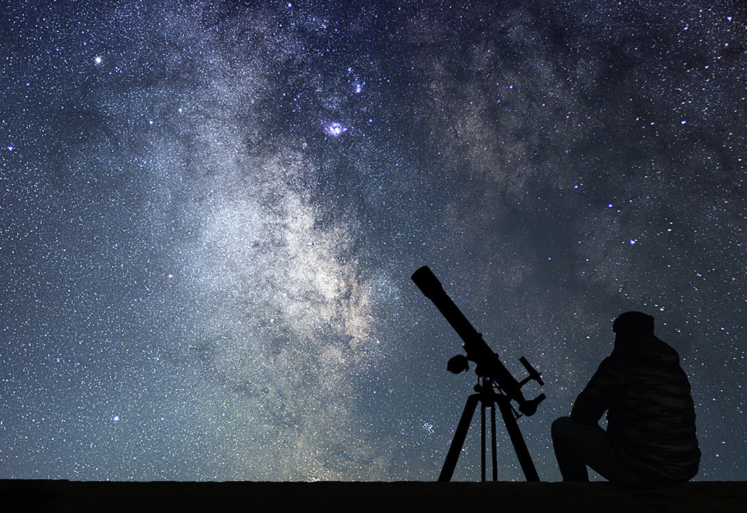 Silueta de hombre y telescopio observando la vía láctea