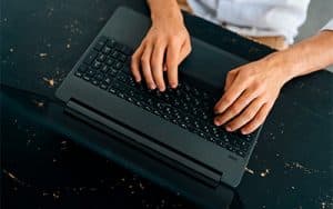 manos en un teclado de portátil negro que anuncian la formación online de espacio moto