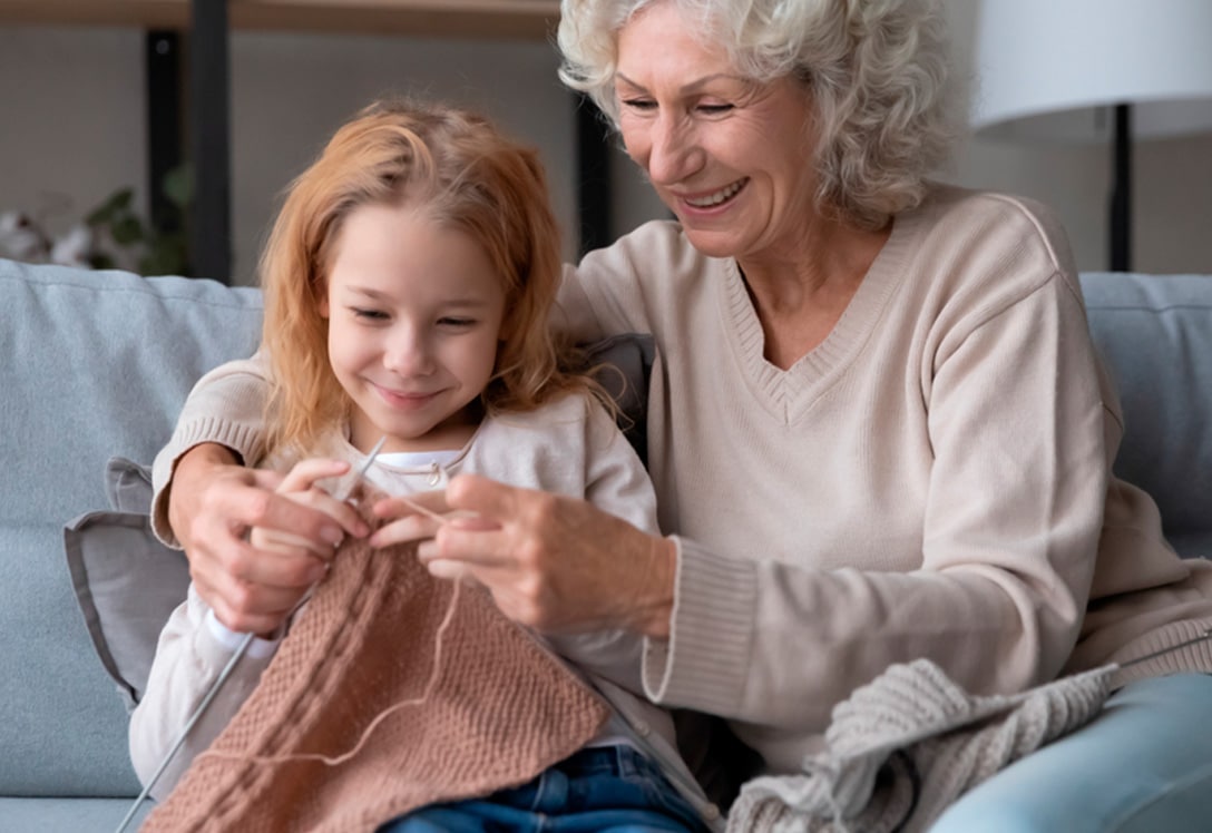 Abuela enseñando a tejer a su nieta