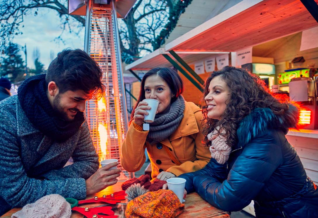 Amigos tomando café en un mercado navideño