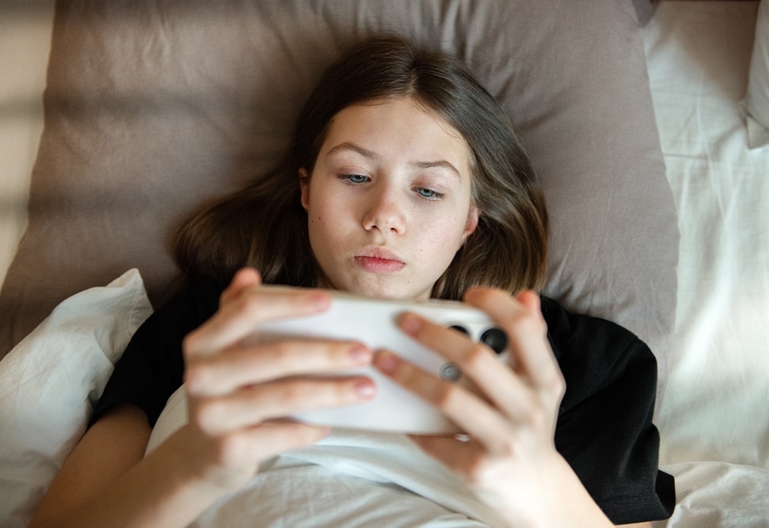 chica-joven-mira-rrss-tumbada chica menos mira redes sociales tumbada en la cama