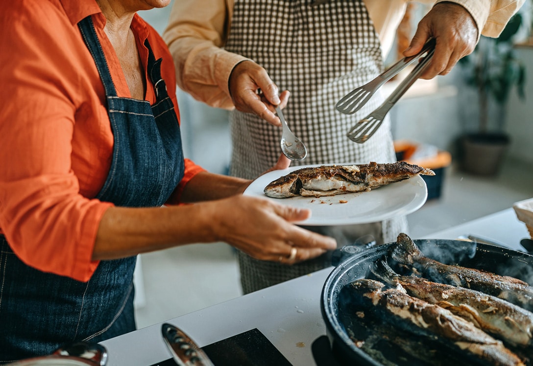 persona sirve a otra pescado blanco en la cocina