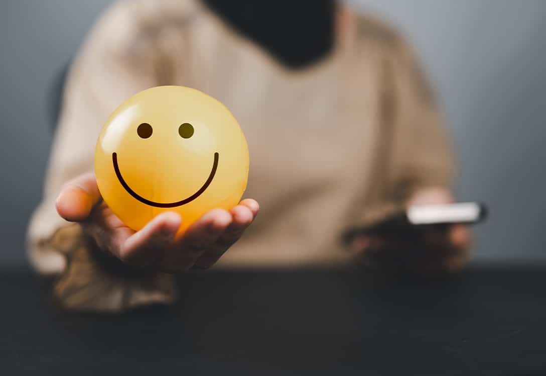 mano con una bola con cara de emoticono sonriente