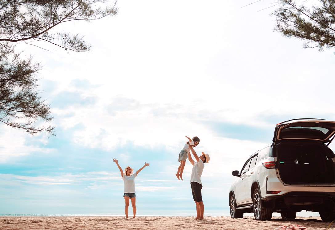 familia disfruta en el exterior en la playa junto a su coche familiar