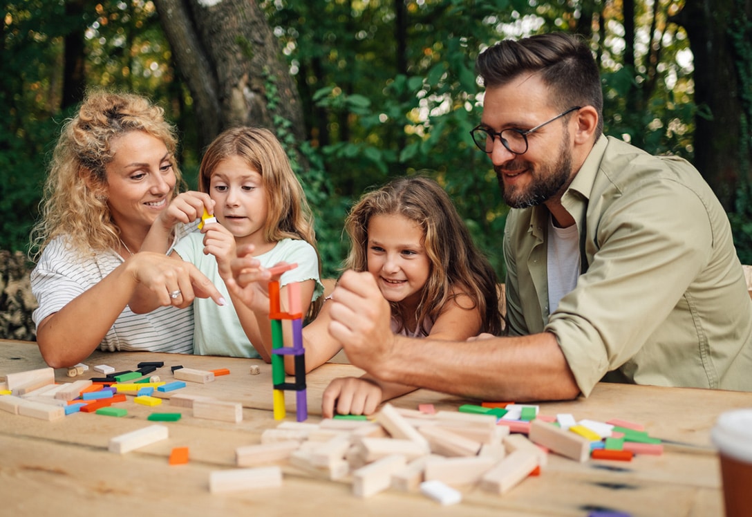 Familia en mesa de campo jugando con sus hijos a juegos de mesa