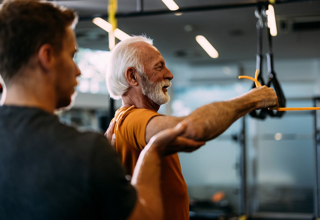 hombre-senior-ejercicios-movilidad-articular-gimnasio hombre mayor haciendo ejercicio en el gimnasio para la movilidad de las artilaciones