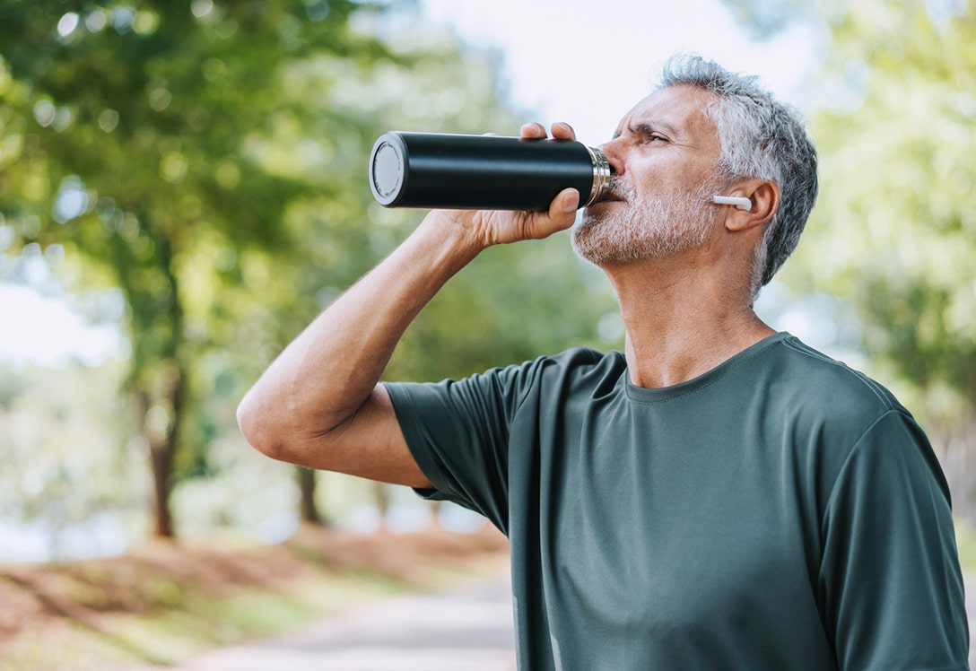 hombre mayor deportista hidratándose en verano