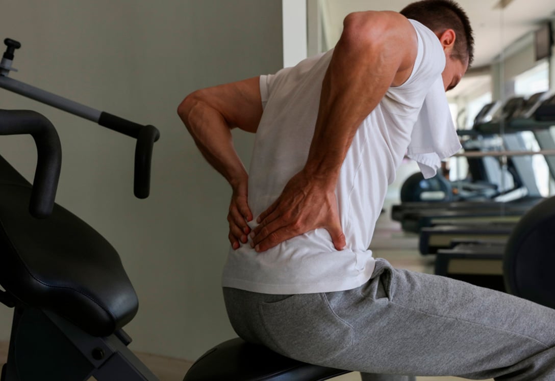 Deportista con lumbalgia en el gimnasio