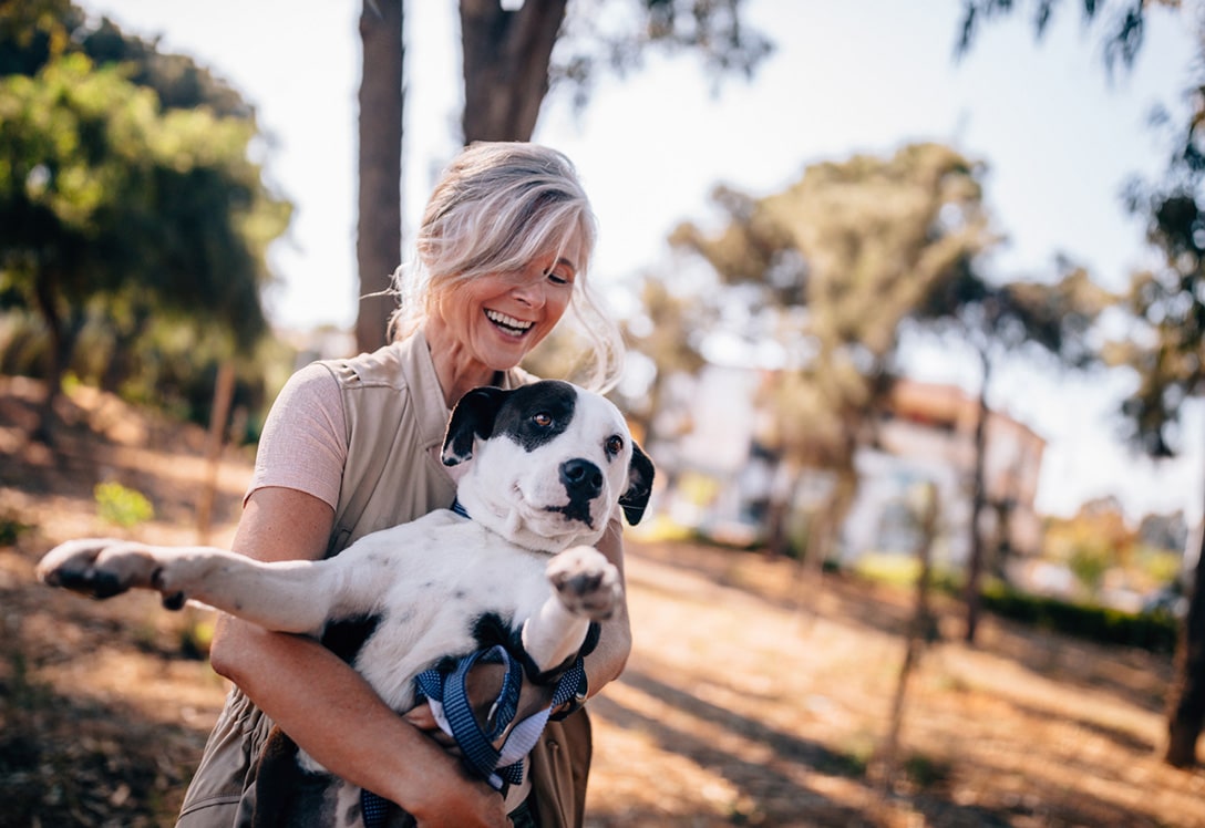 mujer-adiestra-perrro mujer levanta a su perro feliz por su adiestramiento