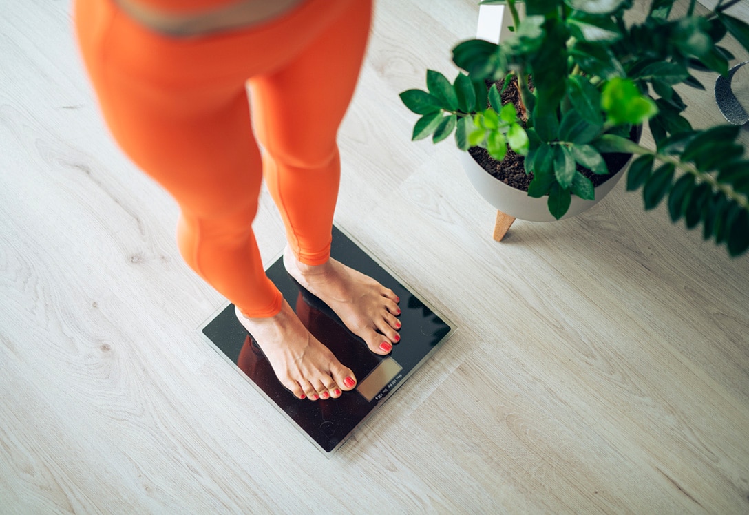mujer sobre bascula para controlar Índice de Masa Muscular (IMC)