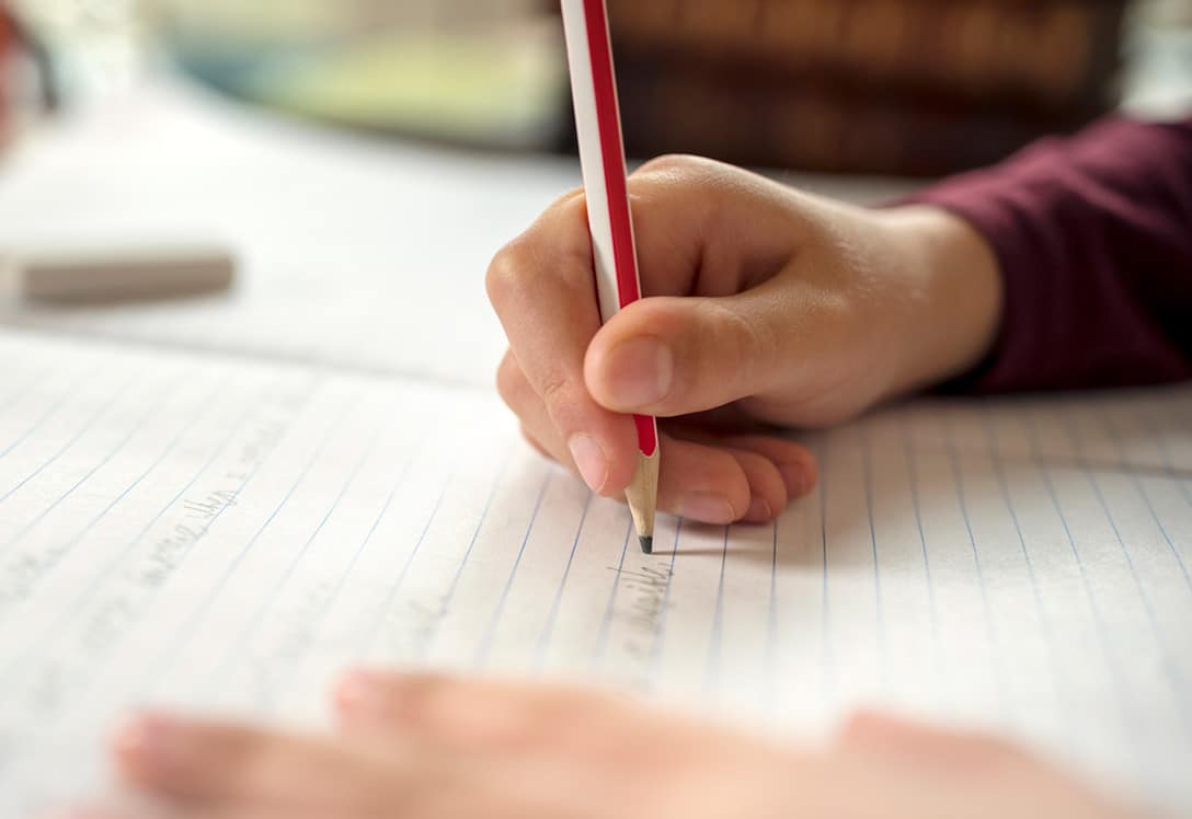 mano de niño con dislexia escribiendo con un lápiz sobre el papel