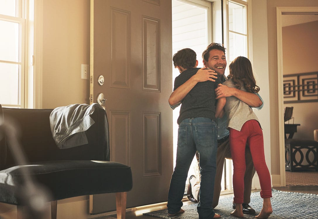 padre abraza a sus hijos en la entrada de casa