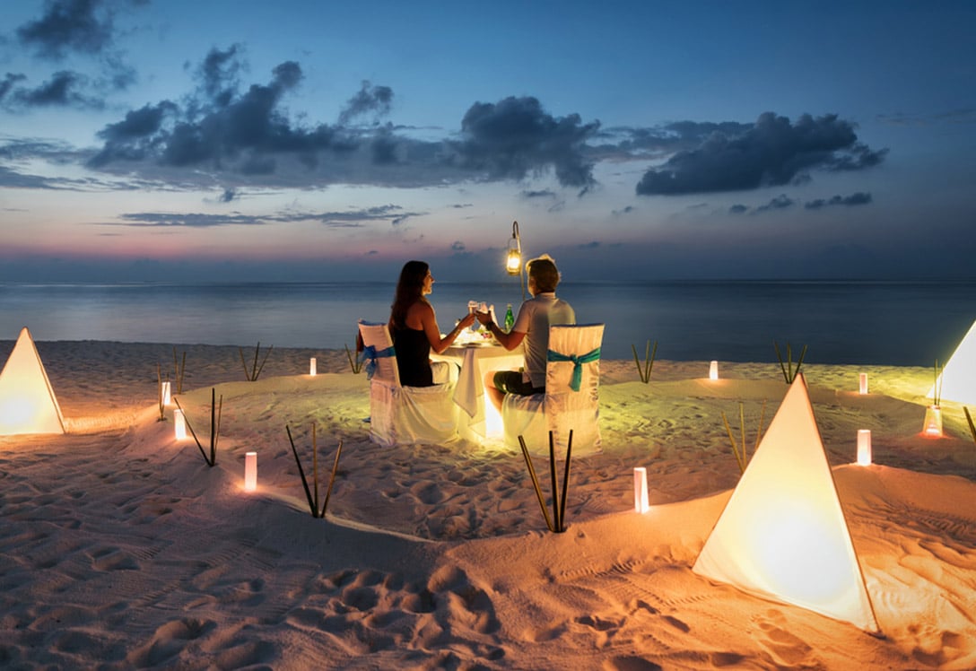 Una pareja cena en la playa al anochecer