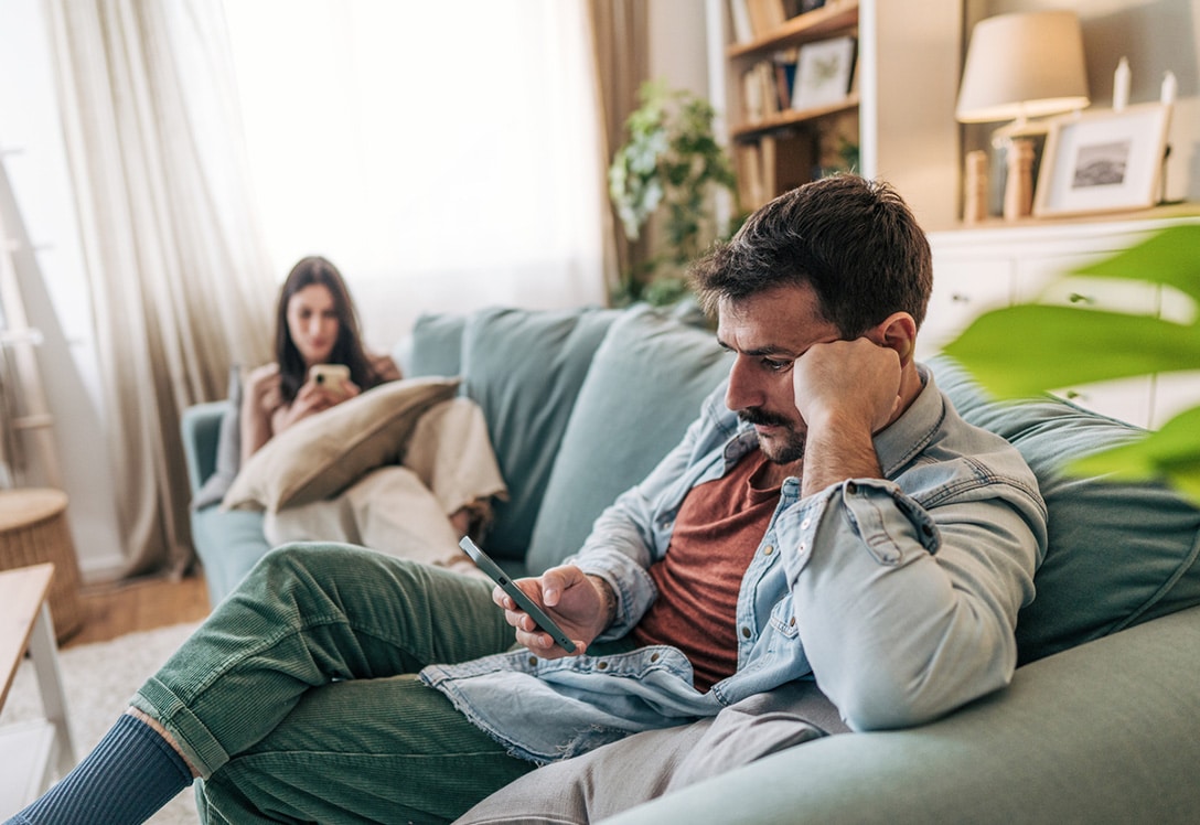 pareja en el sofa sin hablarse mirando sus moviles y sin desconexion digital