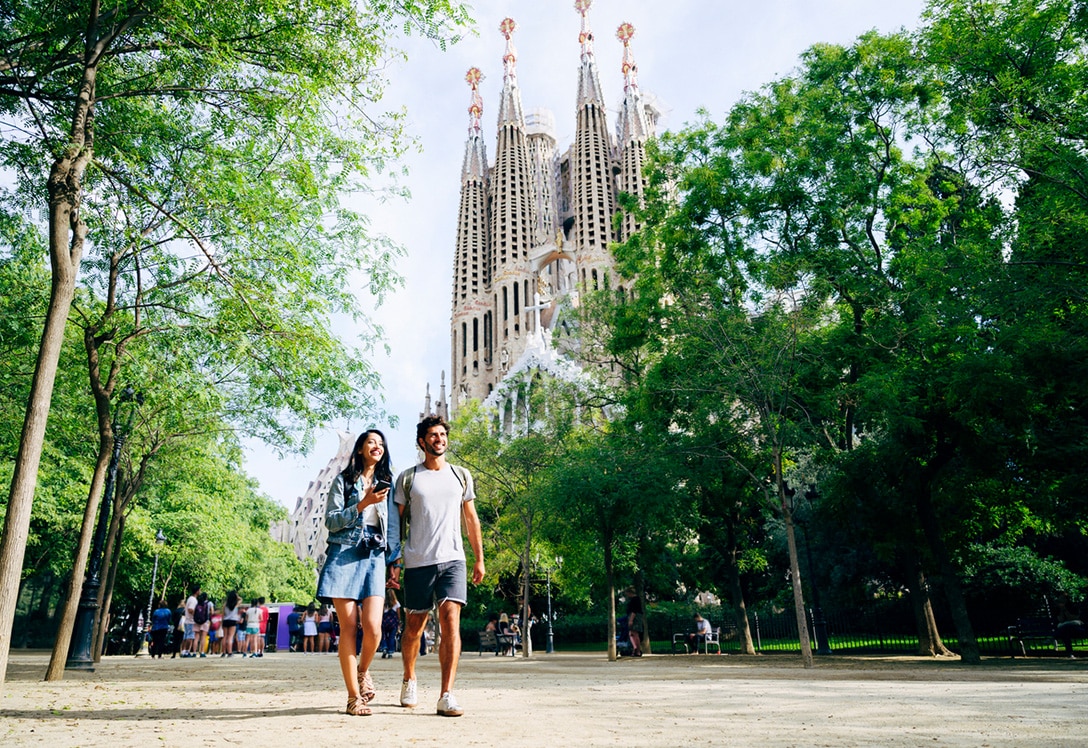 parque-barcelona-sagrada-familia-gaudi pareja pasea en parque y de fondo se observa la Sagrafa familia