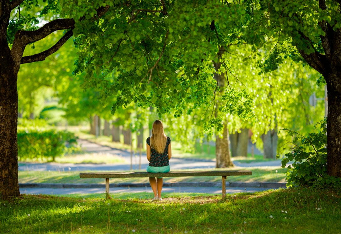 Una chica descansa en un banco de un parque en primavera