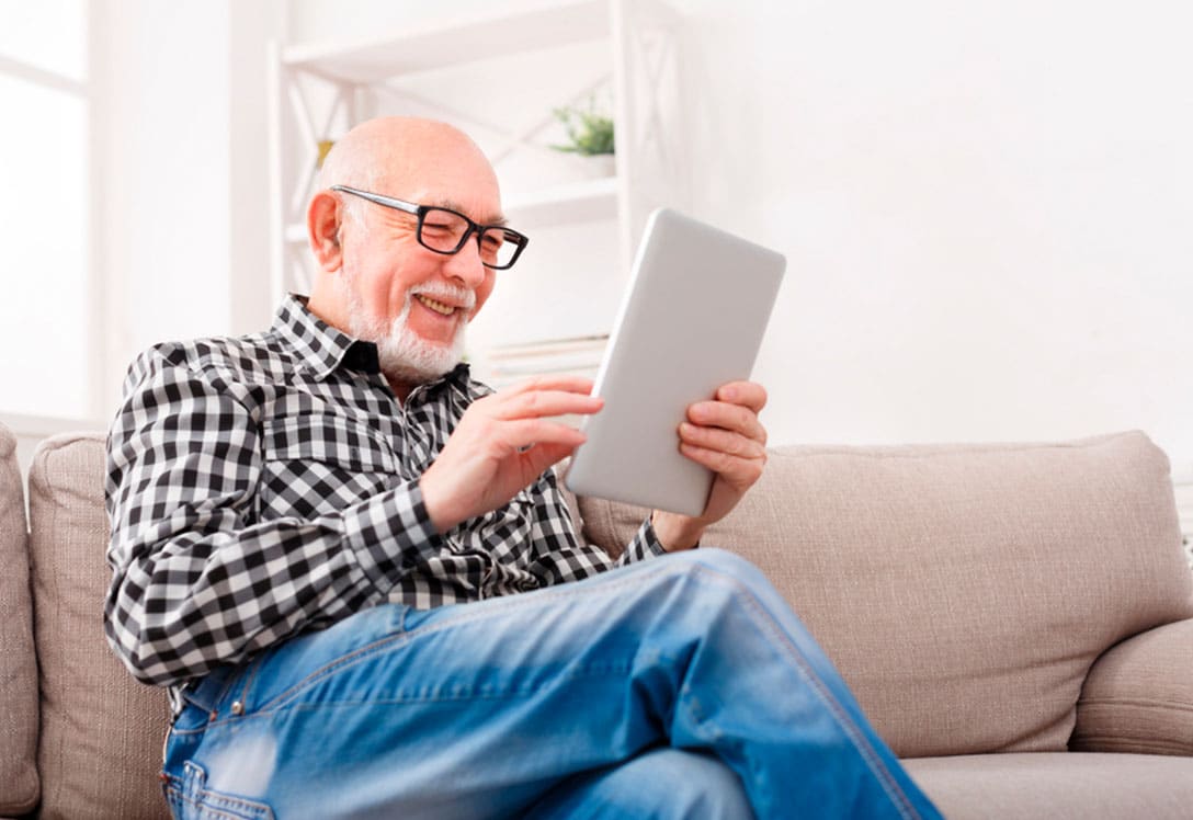 Un hombre mayor revis la tablet en su casa
