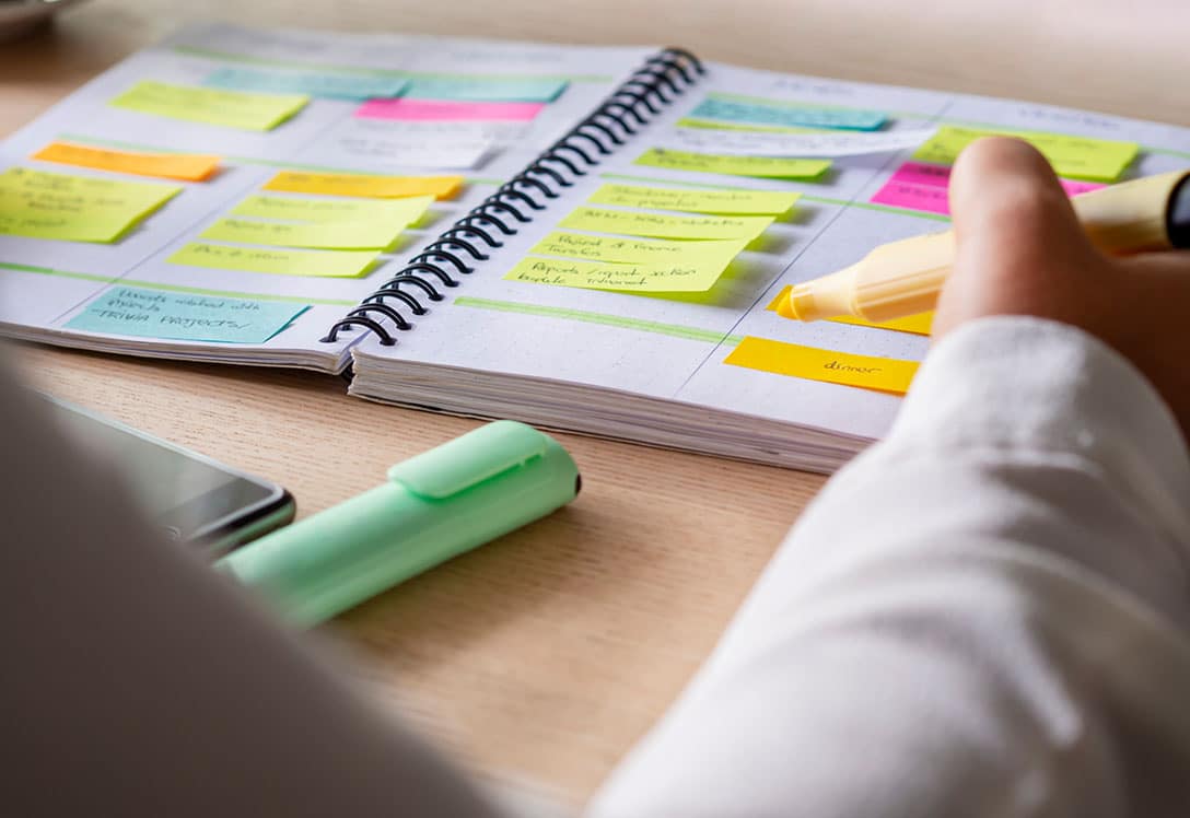 agenda con post-it y mano con subrayador para planificar el tiempo para organizarse