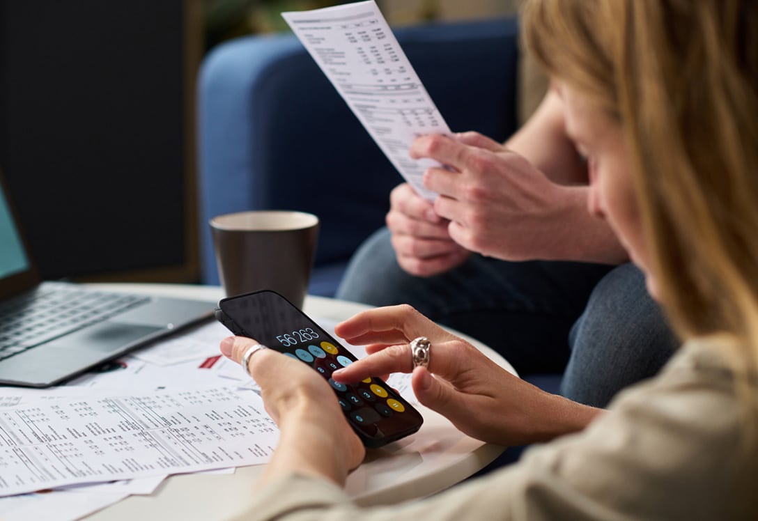2 personas haciendo revisión mensual de sus gastos con calculadora