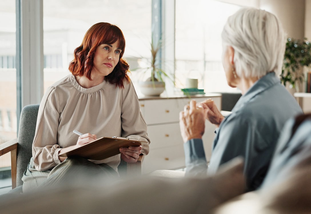 terapia-senior-psicologia-geriatrica Psicóloga escucha y toma nota paciente mayor en la terapia de psicología psiquiátrica.
