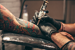 Mujer haciendo un tatuaje en un brazo