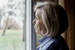 Mujer mayor mirando por la ventana
